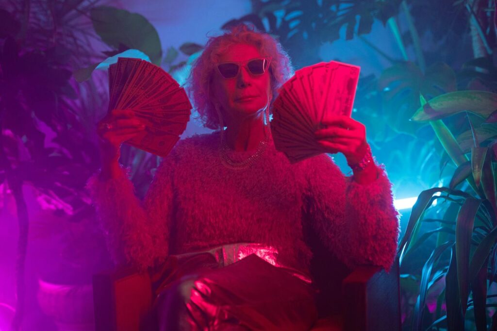 old lady in magenta light enjoying her cash wearing glasses and a fancy skirt